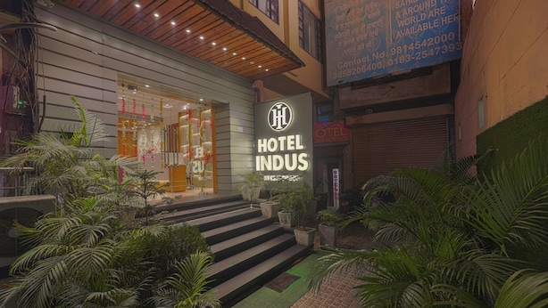 L’entrée d’un hôtel au design moderne, avec une enseigne bien visible, un escalier menant à l’entrée et de la verdure environnante.