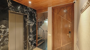 Un couloir avec un mur de marbre, une porte en bois et un escalier menant à un autre étage.