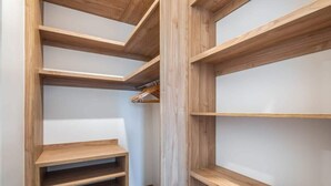 Un armario vestidor con amplios estantes de madera y espacio para colgar.