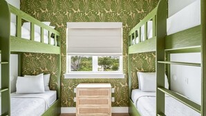 Una habitación con literas, una ventana y un pequeño aparador de madera.