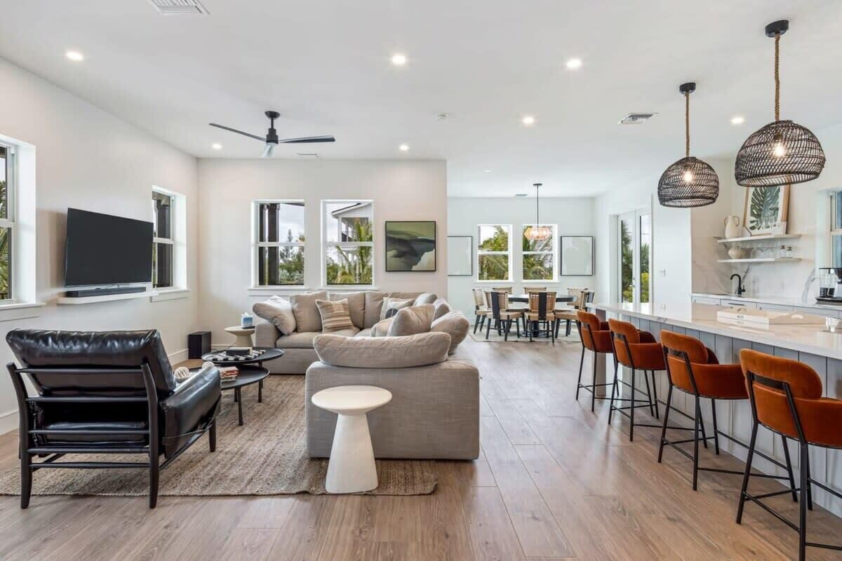 A modern living room with a sofa, a coffee table, and a TV. There is a dining area with a table and chairs.