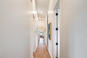Un pasillo con paredes blancas, suelo de madera e imágenes enmarcadas.