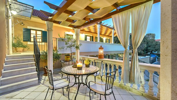 A covered outdoor patio with a round table and chairs, a staircase, and potted plants. - Villa Danica ZadarVillas (Sukošan)