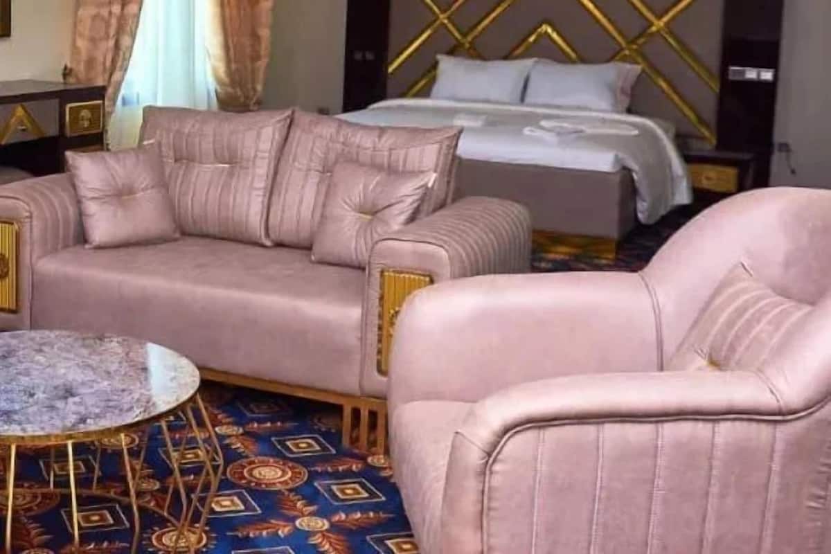 A hotel room with a bed, a sofa, a chair, and a small table.