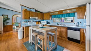Una cocina compacta con armarios de madera, una isla central con taburetes, lavavajillas y microondas.