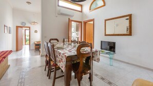A dining area with a table set for four, surrounded by wooden chairs. There is a television on a glass stand to the right, and a large mirror on the wall above it. - 3606 Dimora Incantevole by Barbarhouse (Lecce)