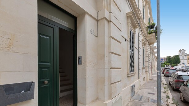 A building with a green door, a mailbox, and a street with parked cars. - 3606 Dimora Incantevole by Barbarhouse (Lecce)