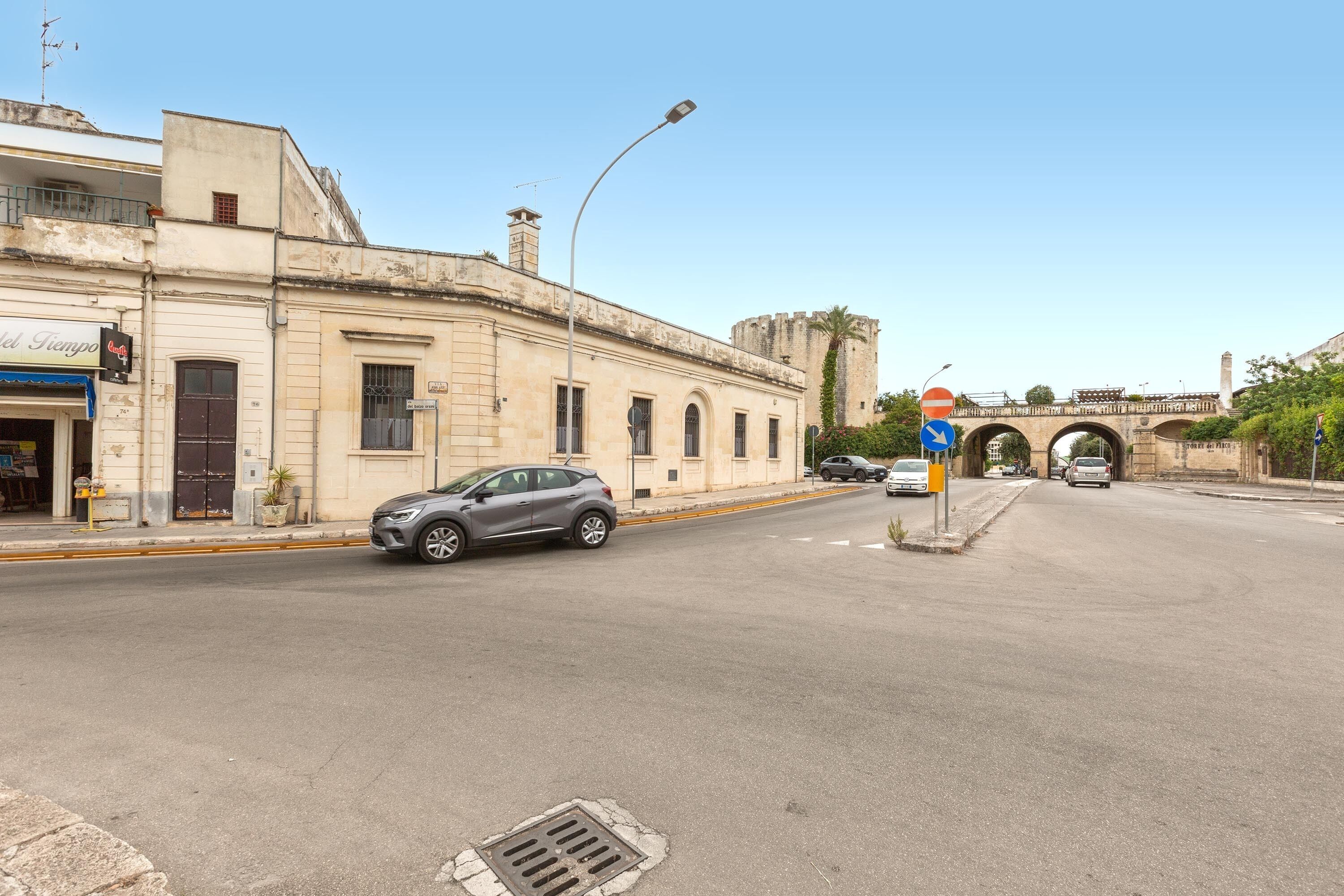 A street with a castle-like structure in the background, a traffic sign, and a building with a sign that reads "El Tempo".