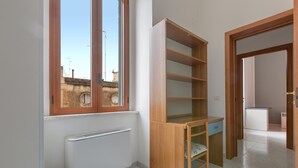 A room with a built-in wooden desk, a radiator, and a window with a view of buildings outside. - 3606 Dimora Incantevole by Barbarhouse (Lecce)
