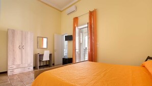 Een slaapkamer met een groot bed, een kledingkast, een bureau en een spiegel.