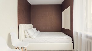 A bedroom with a bed, a chair, and a large window. - Cozy apartment on Vera Khoruzhey street (Minsk)