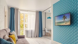 A modern living room with a sofa, curtains, a TV, and a wall with a geometric pattern. - Cozy apartment on Vera Khoruzhey street (Minsk)
