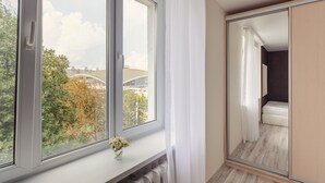 A bedroom with a large window, a mirror, and a view of a bridge and trees. - Cozy apartment on Vera Khoruzhey street (Minsk)