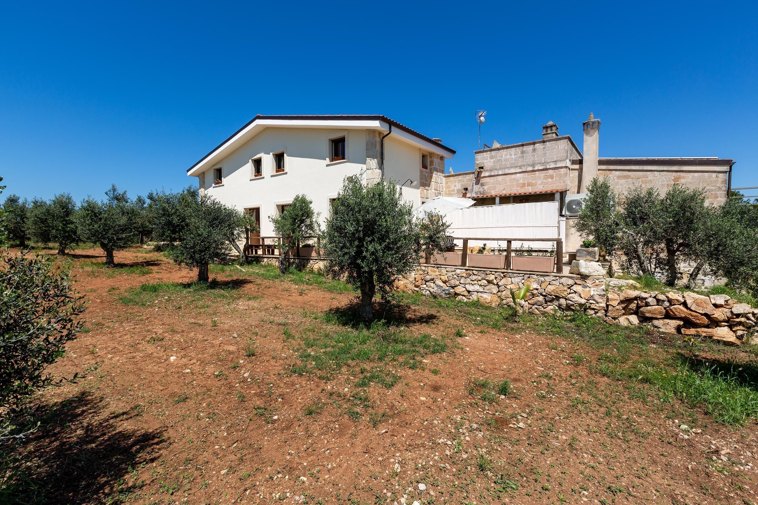 A two-story building with a white facade and a stone wall.