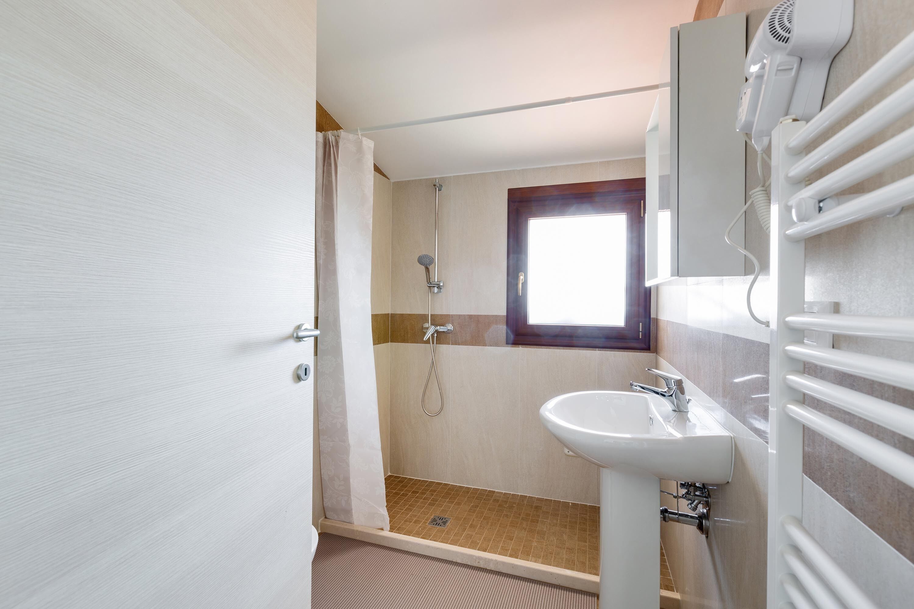 Un baño con ducha, lavabo y toallero.