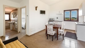 A modern apartment with a dining area, kitchen, and a bedroom with a large bed.