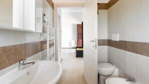 A modern bathroom with a large sink, a toilet, and a bidet.