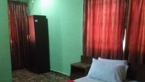 A room with a bed, a wardrobe, and a small table. - Sycamore Royals Hotel Jahi (Abuja)