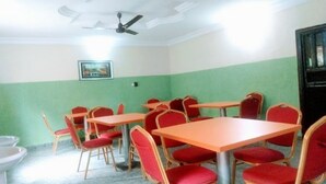 A room with green walls, white ceiling, and a ceiling fan. There are tables and chairs arranged for dining. - Sycamore Royals Hotel Jahi (Abuja)