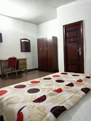 Une chambre à coucher comprenant un lit, un bureau, une chaise et une armoire.