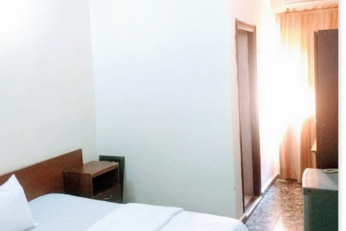 Une chambre d’hôtel équipée d’un lit, d’une table de chevet, d’une armoire et d’un ventilateur de plafond.