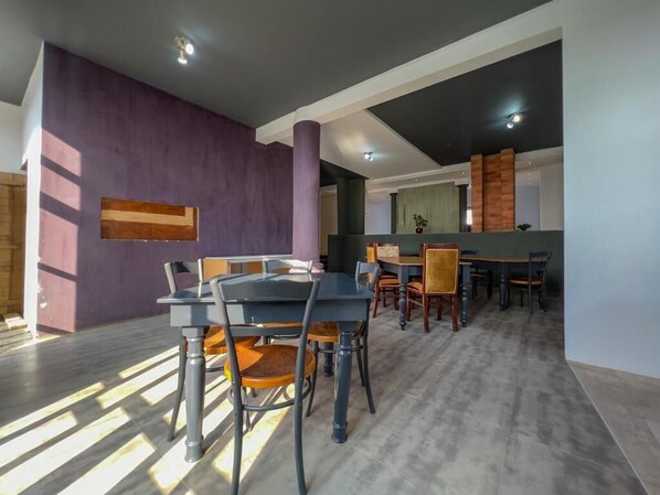 Un comedor moderno con una pared de acento púrpura, muebles de madera y vistas a otra habitación.