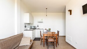 Un espacio habitable compacto con kitchenette, comedor con mobiliario de madera y sofá.
