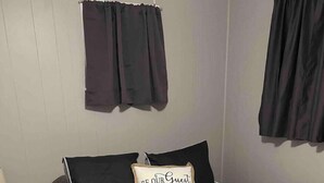 Ein Schlafzimmer mit einem Bett, einem Nachttisch, einer Lampe und einem Wandvorhang.