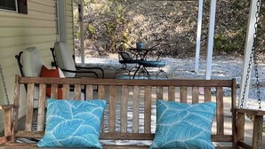 Eine hölzerne Veranda mit einer Bank und zwei blauen Kissen mit Muster.