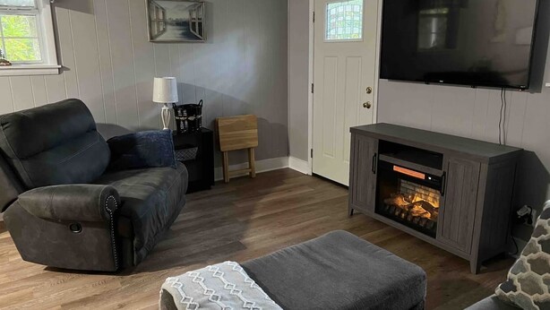 Ein Wohnzimmer mit einer Ledersofa, einem kleinen Holztisch, einem an der Wand montierten Fernseher und einem Kamin.
