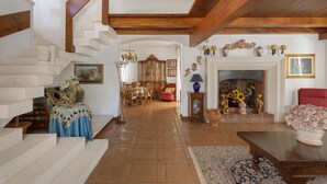 Uma sala de estar ampla com escada, lareira e espaço de jantar.