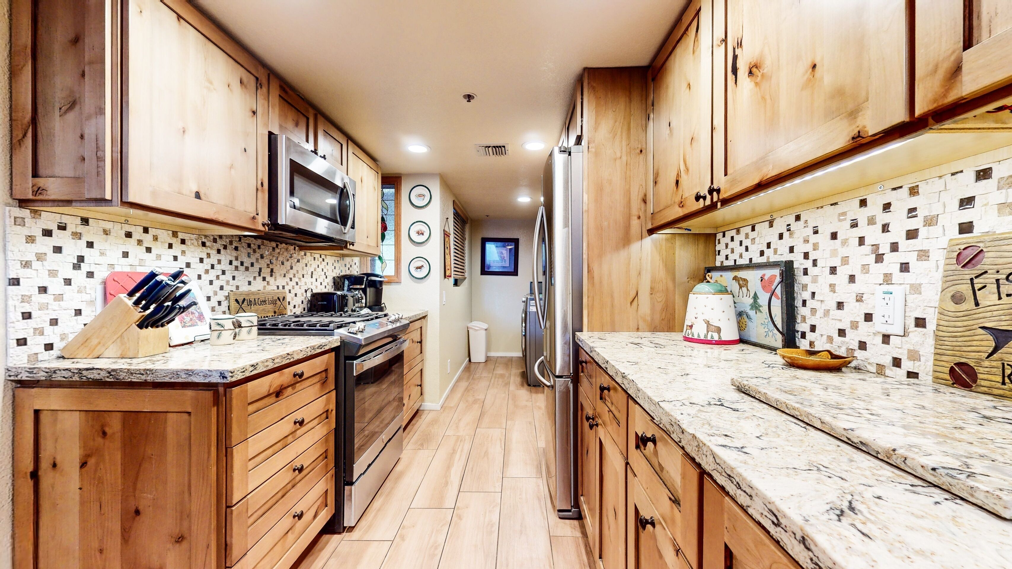 Una cocina con armarios de madera, microondas, estufa y refrigerador.