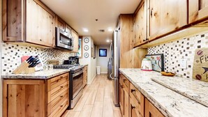 A kitchen with wooden cabinets, a microwave, stove, and a refrigerator. - Bridges #108 2 Bedroom Condo by RedAwning (Mammoth Lakes)