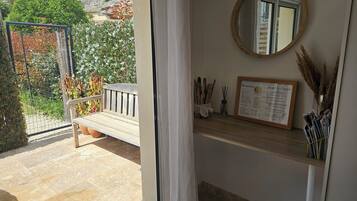 Une pièce avec un banc en bois, un miroir, un panneau d’accueil et une étagère contenant des magazines et des bâtonnets de roseau.