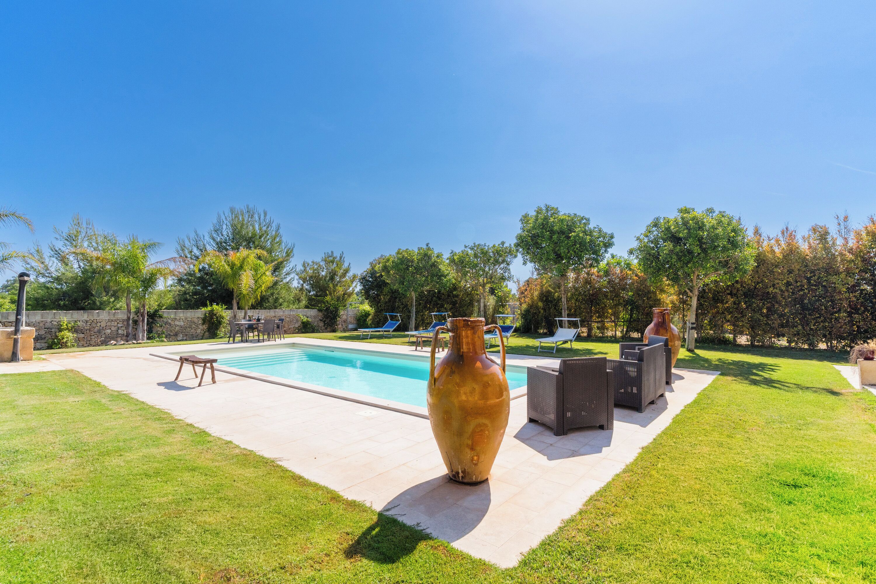 A backyard with a swimming pool, outdoor furniture, and a large vase.