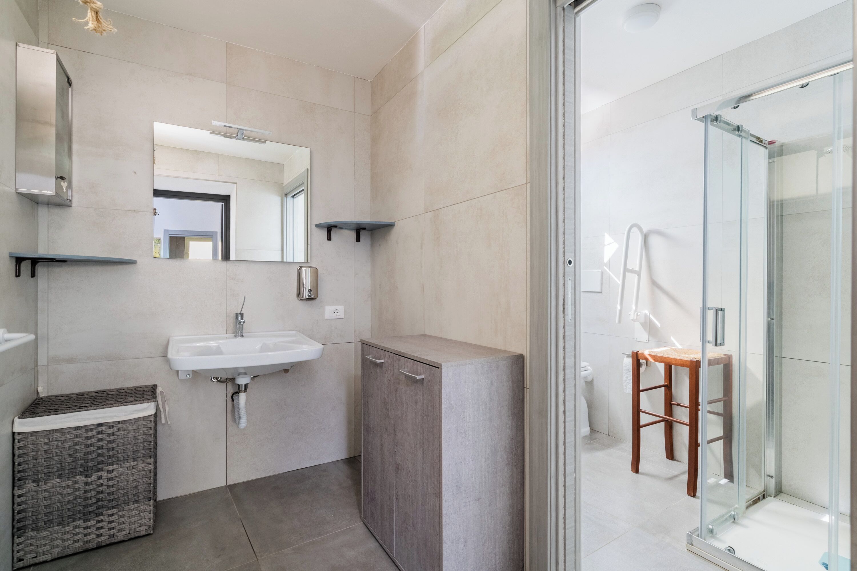 A modern bathroom with a sink, mirror, cabinet, and glass shower enclosure.