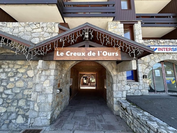Entrada de un edificio de piedra con un letrero que dice 'Le Creux de l'Ours'.