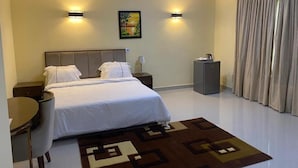Habitació d'hotel moderna amb un llit gran, dues taules de nit, un escriptori i una cadira. Hi ha dues làmpades penjades a la paret i un quadre.