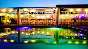 Zona de piscina amb seients escalonats i decoracions de teixits penjants.