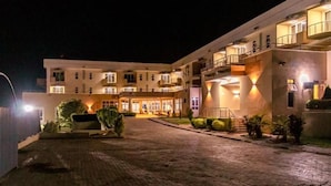 Hotel de diversos pisos amb un pati central, il·luminació exterior i una zona d'entrada pavimentada.