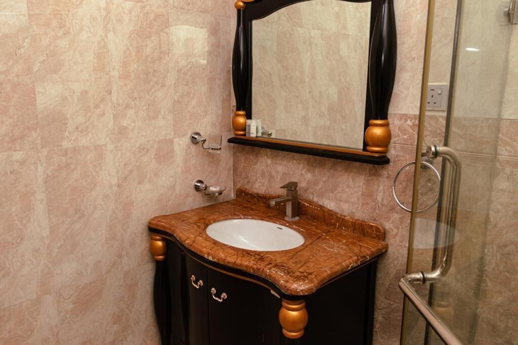 A bathroom with a marble sink, a mirror, and a glass shower enclosure.