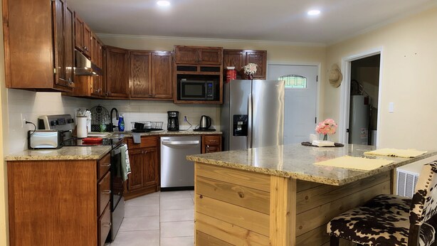 A modern kitchen with wooden cabinets, stainless steel appliances, and a granite countertop.