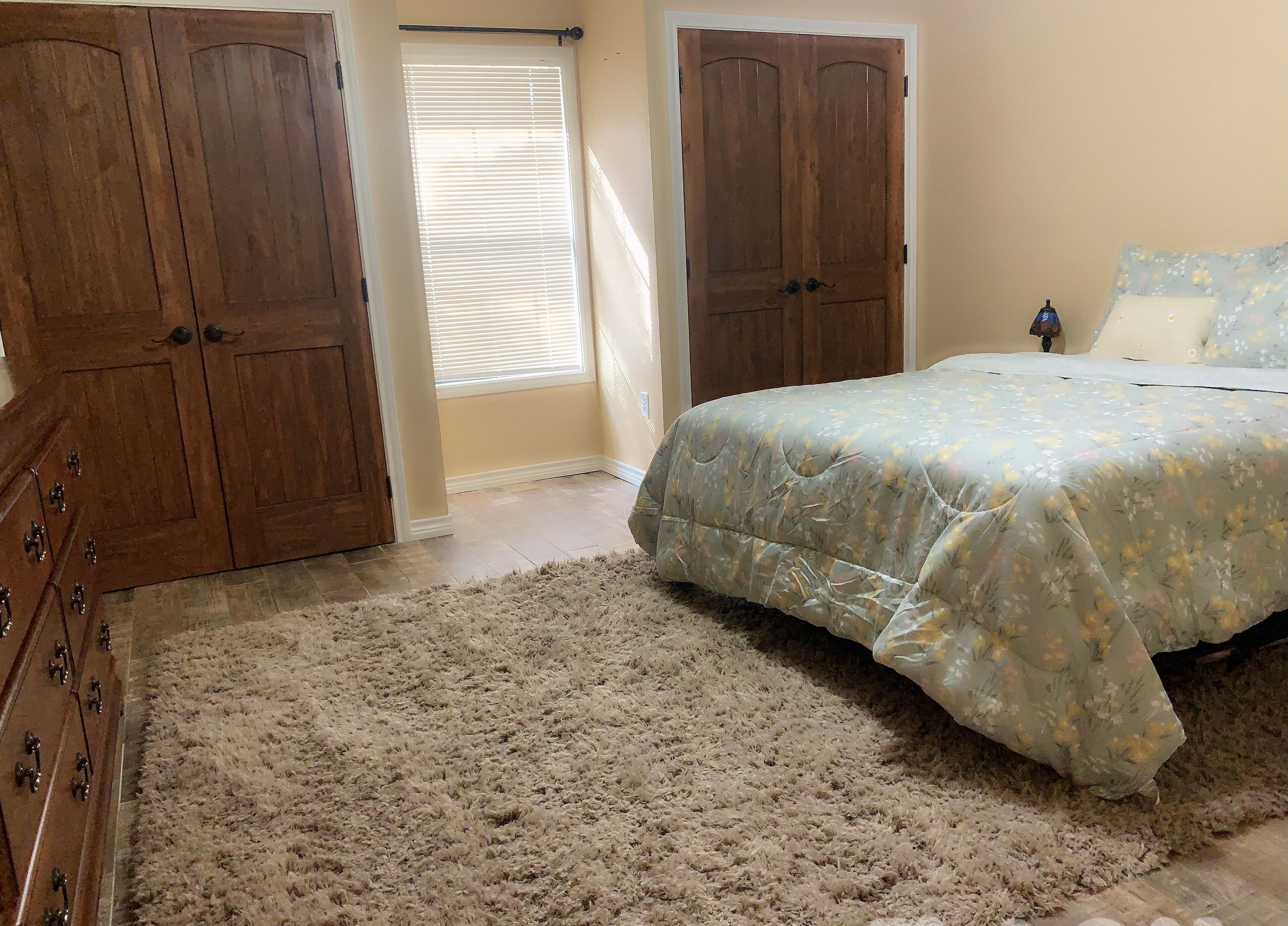 Una camera da letto con un letto, una cassettiera e due porte in legno.