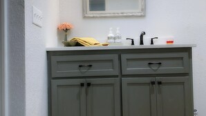 A bathroom with a double vanity, a mirror, and a light fixture above the mirror.