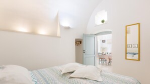 Ein Schlafzimmer mit einem Bett, einem Spiegel und einer Tür zum Essbereich.