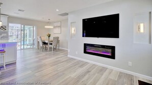Een moderne woonkamer met een flatscreen televisie, een open haard en een eethoek.