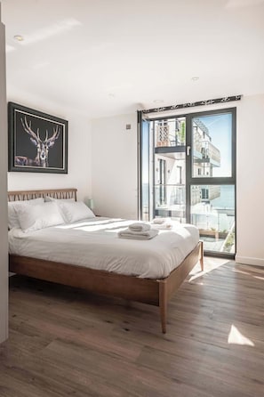 A bedroom with a bed, a framed deer artwork, and a balcony with a view.
