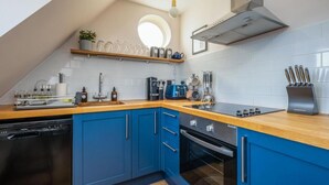 A modern kitchen with blue cabinets, a wooden countertop, and a built-in oven.