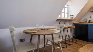 A kitchen with a round wooden table, two chairs, and a black dishwasher.