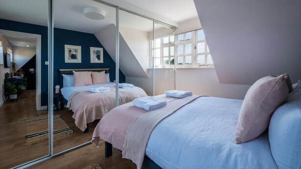 A bedroom with two beds, a large mirror, and a view of a balcony.